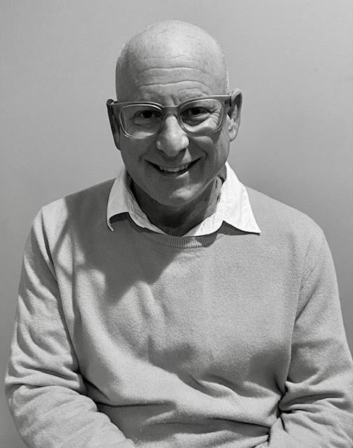 A man with bald head and glasses smiling for the camera.